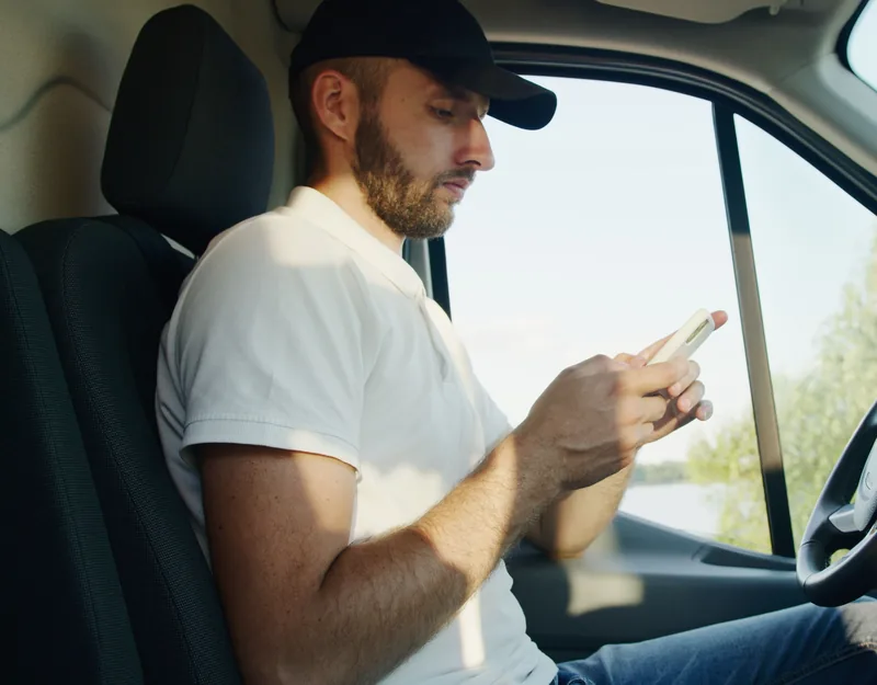 Man in a work van checking his phone