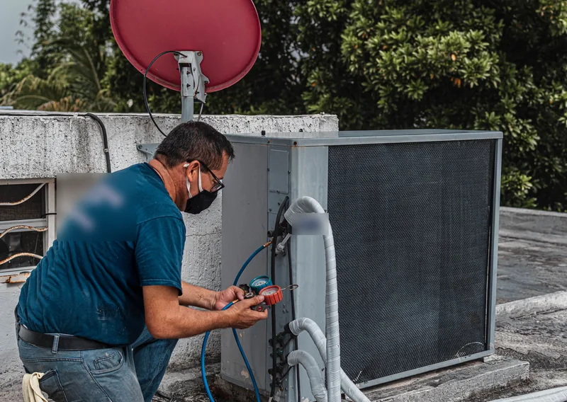 HVAC technician checking refrigerant gauges at an outdoor unit